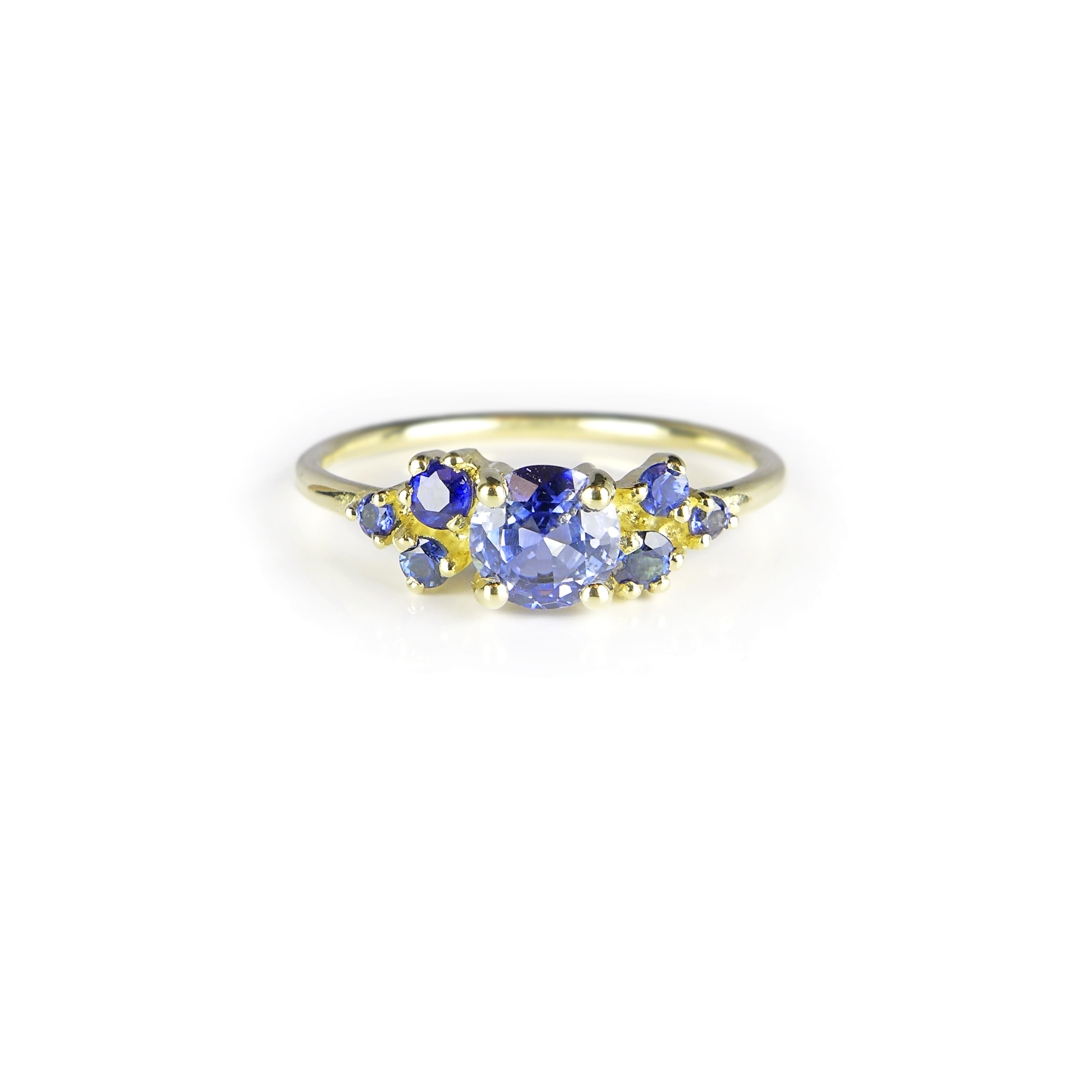 yellow golden delicate ring with a big blue round sapphire in the middle and six smaller ones next to it